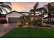 Beautiful one-story home featuring a three-car garage, brick-paved driveway, and lush tropical landscaping at sunset at 3814 Scrub Creek Run, Lakewood Ranch, FL 34211