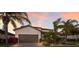 Charming home featuring a two-car garage, a stone-accented facade, and tropical landscaping at sunset at 3814 Scrub Creek Run, Lakewood Ranch, FL 34211