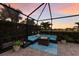 Screened patio with a brick floor is furnished with a conversation set, a fire table, and tropical landscaping at 3814 Scrub Creek Run, Lakewood Ranch, FL 34211
