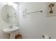 Simple powder room with pedestal sink, round mirror, and tropical-themed wall art at 3814 Scrub Creek Run, Lakewood Ranch, FL 34211