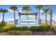 Elegant community entrance sign surrounded by lush greenery and mature palm trees at 4021 Direct Greeen Pl, Bradenton, FL 34208