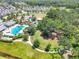Aerial view of a community featuring a pool, clubhouse, playground, and sports field nestled among lush trees at 4107 Pine Meadow Dr, Parrish, FL 34219