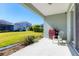View of an open back patio with a grill and a chair, overlooking the well-maintained backyard and neighboring homes at 4107 Pine Meadow Dr, Parrish, FL 34219