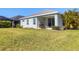 Backyard view with a grill on a covered patio, lush green lawn, and neighboring house at 4107 Pine Meadow Dr, Parrish, FL 34219