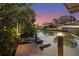 Evening shot of a waterfront with jet skis and a boat, surrounded by tropical foliage, lit by dock lights at 4109 Cobia Ct, Palmetto, FL 34221