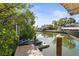 Waterfront view of a wooden dock with jet skis and a boat, surrounded by tropical foliage at 4109 Cobia Ct, Palmetto, FL 34221