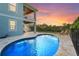 Backyard pool with a stone patio, lounge chairs, and a covered seating area overlooks the sunset at 4109 Cobia Ct, Palmetto, FL 34221