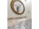 Bathroom features a round mirror, granite countertop, white cabinet, and decorative knobs at 425 30Th W Ave # C208, Bradenton, FL 34205