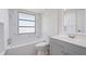 Well-lit bathroom with white marble-style tile, a bathtub with shower, and vanity with storage at 425 Skylark Nw Ln, Port Charlotte, FL 33952