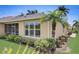 Tan home exterior with a well-manicured lawn and tropical landscaping under a clear sky at 4250 Turnberry Cir, North Port, FL 34288