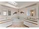 Luxurious bathroom featuring double sinks, a soaking tub, tile flooring, and a unique skylight with decorative accents at 4655 Payne St, North Port, FL 34287