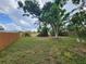 View of a large, grassy backyard enclosed by a wooden fence, featuring mature trees and plenty of space at 4712 Cronin Dr, Sarasota, FL 34232