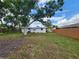 A wide-open backyard featuring green grass, mature trees and partial fencing; view of the back of the house at 4712 Cronin Dr, Sarasota, FL 34232