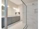 Modern bathroom featuring a double vanity with gray cabinets and a glass enclosed walk-in shower with marble tile at 5673 Piccolo St, Nokomis, FL 34275