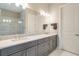 Bathroom features double sinks with gray cabinetry, granite countertop, large mirror, and modern lighting fixtures at 5673 Piccolo St, Nokomis, FL 34275