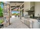 Covered outdoor kitchen and bar area with a grill, sink, and counter space, great for entertaining at 5673 Piccolo St, Nokomis, FL 34275