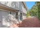 Rear exterior shot showing white siding, brick patio, mature landscaping, and blue skies at 5766 Forester Pine Ct, Sarasota, FL 34243