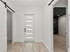 Bright entryway featuring light wood floors, a modern front door with glass panes, and barn doors at 5838 Meriwether Pl, Sarasota, FL 34232