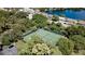 Aerial view of tennis court surrounded by lush trees, a lake and nearby townhomes creating an active and serene community space at 631 Woodlawn Dr, Bradenton, FL 34210