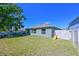 Side view of a spacious back yard enclosed with white fencing, showcasing a home with neutral exterior at 6723 Trent Creek Dr, Sun City Center, FL 33573