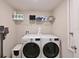 Bright laundry room features white washer and dryer, a convenient storage shelf, and a mounted vacuum cleaner at 6723 Trent Creek Dr, Sun City Center, FL 33573