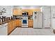 Corner kitchen with wood cabinetry, white appliances, and tile flooring throughout the area at 7180 83Rd E Dr # 6-5, Bradenton, FL 34201