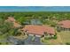 Stunning aerial view of a residential home with a terracotta roof next to a tranquil lake surrounded by lush greenery at 7269 Golf Pointe Way, Sarasota, FL 34243
