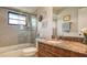 Bathroom with tan and brown granite countertop, wood cabinets, and glass enclosed shower tub combination at 7269 Golf Pointe Way, Sarasota, FL 34243