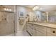 Bright bathroom features a double vanity with stone countertop and walk-in shower with glass door at 7269 Golf Pointe Way, Sarasota, FL 34243