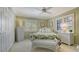 Bedroom with green walls, tropical patterned comforter, and bright natural light from the windows at 7269 Golf Pointe Way, Sarasota, FL 34243