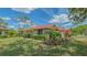 Landscaped home exterior with a well-manicured lawn, red tile roof, and lovely blooming plants at 7269 Golf Pointe Way, Sarasota, FL 34243
