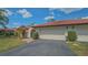 Townhome showcasing a red tile roof, manicured landscaping, and attached garage at 7269 Golf Pointe Way, Sarasota, FL 34243