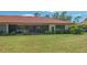 Rear exterior view featuring a manicured lawn, screened lanai, and lush landscaping surrounding the home at 7269 Golf Pointe Way, Sarasota, FL 34243