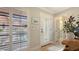 Bright foyer with a decorative glass front door, white trim, and a view to the outdoor patio through shuttered windows at 7269 Golf Pointe Way, Sarasota, FL 34243