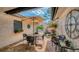 Charming outdoor patio with brick flooring, seating under an umbrella, and views of the gated entrance and lush landscaping at 7269 Golf Pointe Way, Sarasota, FL 34243