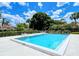 Community pool with clear blue water, poolside seating, and tropical landscaping under a bright sky at 7269 Golf Pointe Way, Sarasota, FL 34243