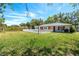 Backyard with green grass, mature trees, a fenced-in pool, and a home with red accents at 7299 S Leewynn Dr, Sarasota, FL 34240