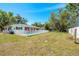 Backyard pool with white fence, grassy area, and house with red accents, perfect for outdoor entertaining at 7299 S Leewynn Dr, Sarasota, FL 34240