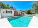 Backyard pool with a white fence, house with red accents, and lush green trees, for privacy at 7299 S Leewynn Dr, Sarasota, FL 34240