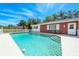 Backyard view of the pool with a white fence, house with red accents, and steps to the pool at 7299 S Leewynn Dr, Sarasota, FL 34240