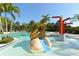 Fun splash pad and play structure next to community pool surrounded by tropical palm trees at 7407 Green St, Bradenton, FL 34201