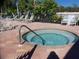 A relaxing hot tub area with lounge chairs, lush greenery, and a black metal fence at 7554 Camden Harbour Dr, Bradenton, FL 34212