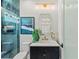 Modern bathroom features stylish vanity, gold fixtures, sleek glass shower, and eye-catching turquoise tile at 800 Blue Shell Loop, Sarasota, FL 34240