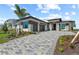 Modern home with a paver driveway, three-car garage, and meticulously landscaped front yard with palm tree at 800 Blue Shell Loop, Sarasota, FL 34240