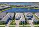 Stunning aerial view of a modern home with a tile roof and paver driveway, surrounded by lush landscaping and a serene lake at 8335 Sea Glass Ct, Sarasota, FL 34240