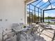 An outdoor patio dining area with a contemporary table, chairs, and a tranquil view of the pool and waterfront landscape at 8335 Sea Glass Ct, Sarasota, FL 34240