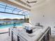 A serene outdoor patio with a cozy sectional, a view of the pool, and a picturesque lake framed by a screened enclosure at 8335 Sea Glass Ct, Sarasota, FL 34240