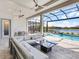 A luxurious outdoor patio featuring a modern sectional, sleek coffee table, and stunning lake and pool views at 8335 Sea Glass Ct, Sarasota, FL 34240