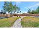Well-manicured backyard with a brick-paved path leading to a fire pit, surrounded by a wooden privacy fence at 8419 Sylvan Woods Dr, Sarasota, FL 34243