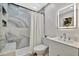 Updated bathroom featuring a shower with marble-look tile, modern vanity, and lighted mirror at 8419 Sylvan Woods Dr, Sarasota, FL 34243